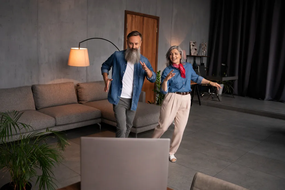 Adults of different ages following a dance lesson on a television at home